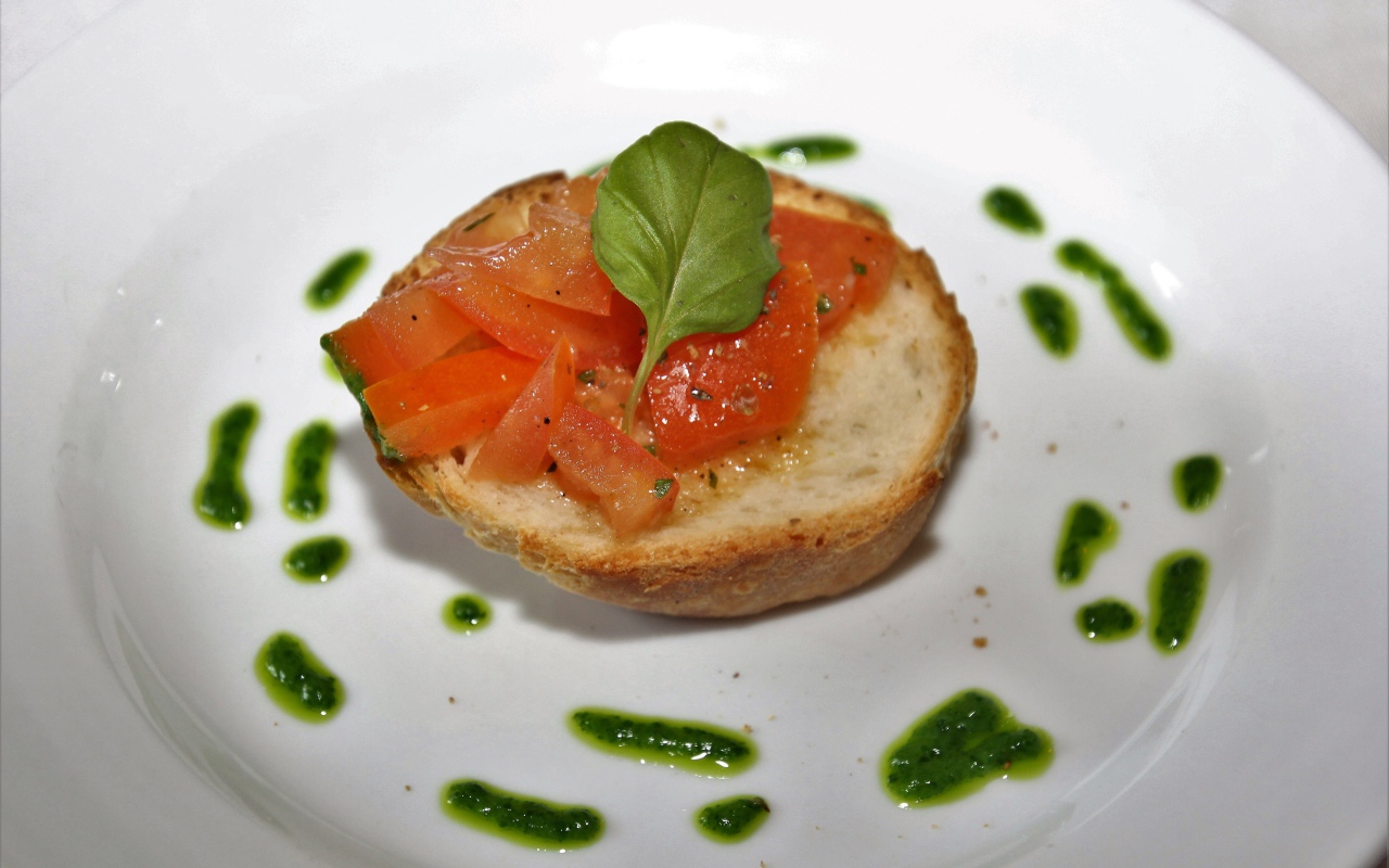 Брускетта на тарелке с помидорами и соусом