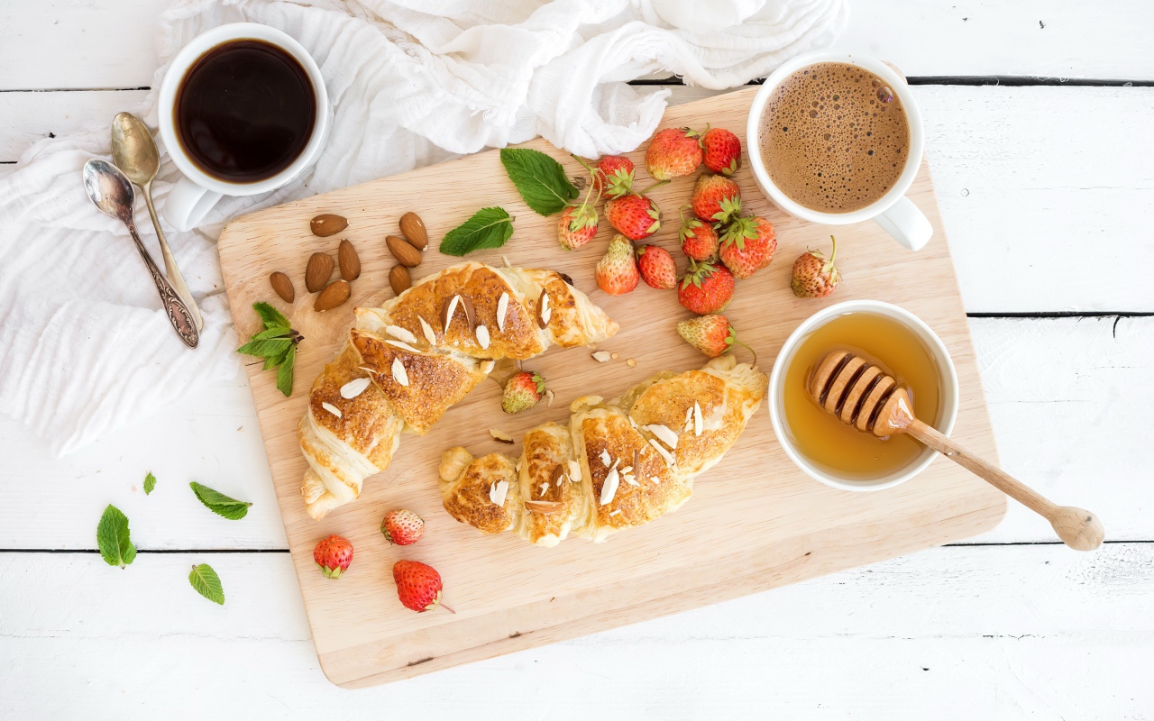Круассаны на столе с орехами, клубникой и кофе