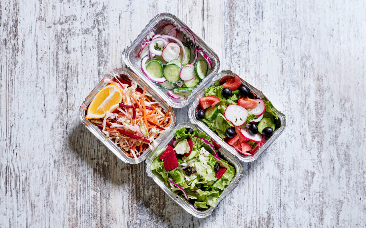 Разные овощные салаты в тарелках на сером столе 