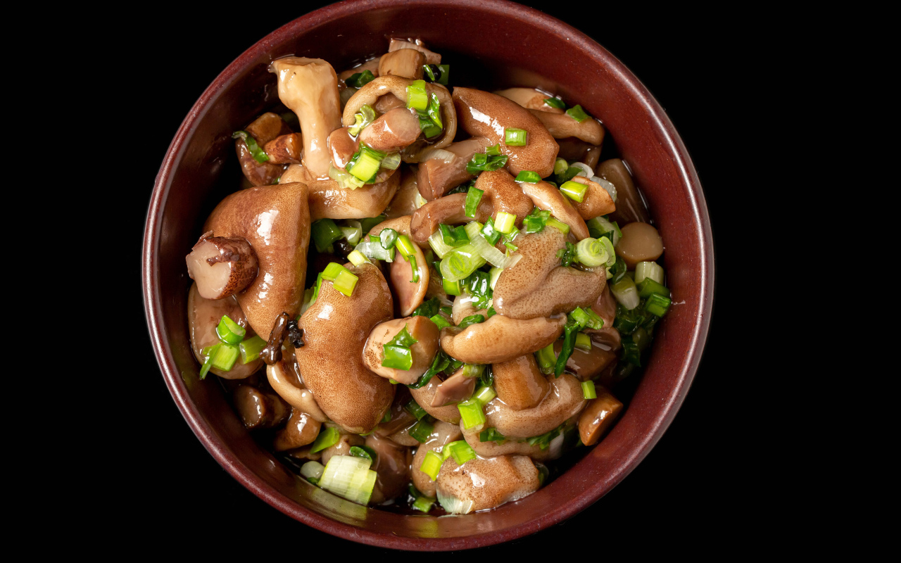 Маринованные маслята с зеленью в тарелке