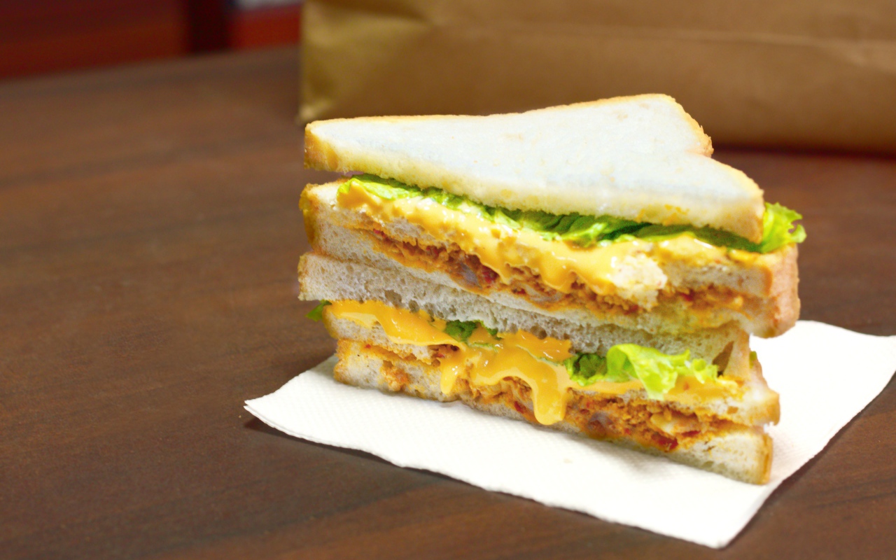 Сэндвич с сыром и листьями салата на столе