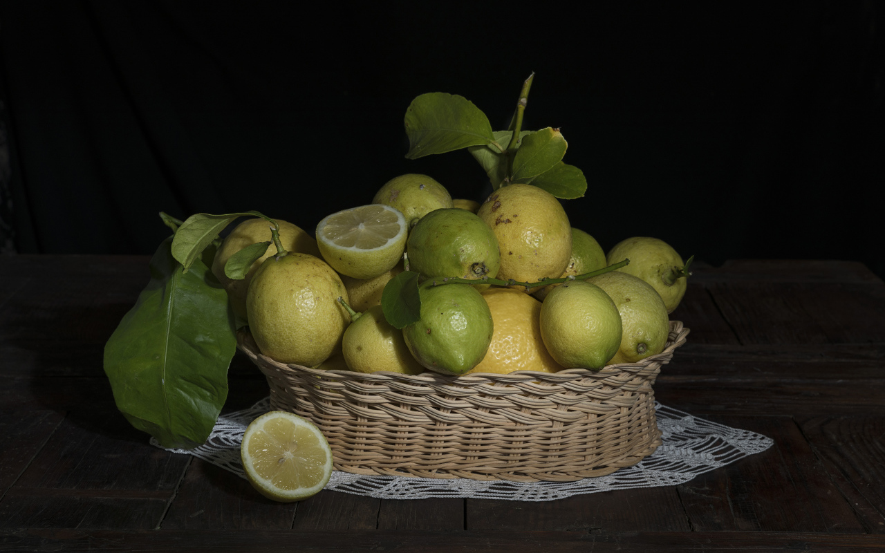 Lemons and limes in a wicker basket on a black background