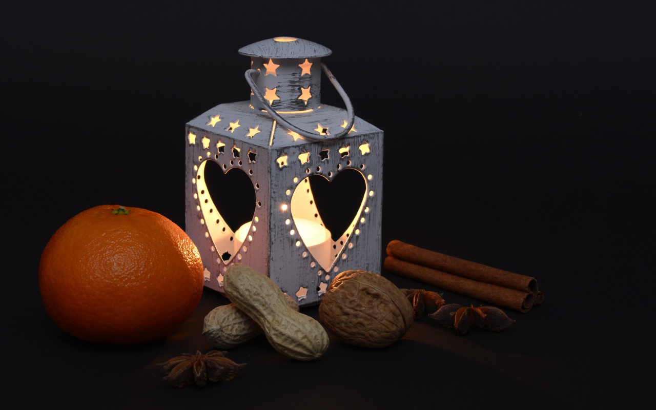 Мандарин, орехи, специи и фонарь на черном фоне