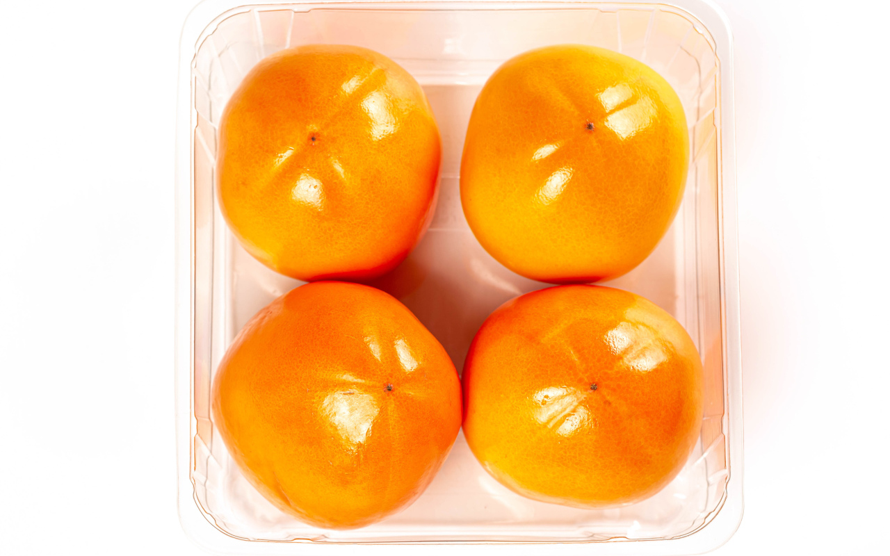 Спелая хурма с лотке на белом фоне