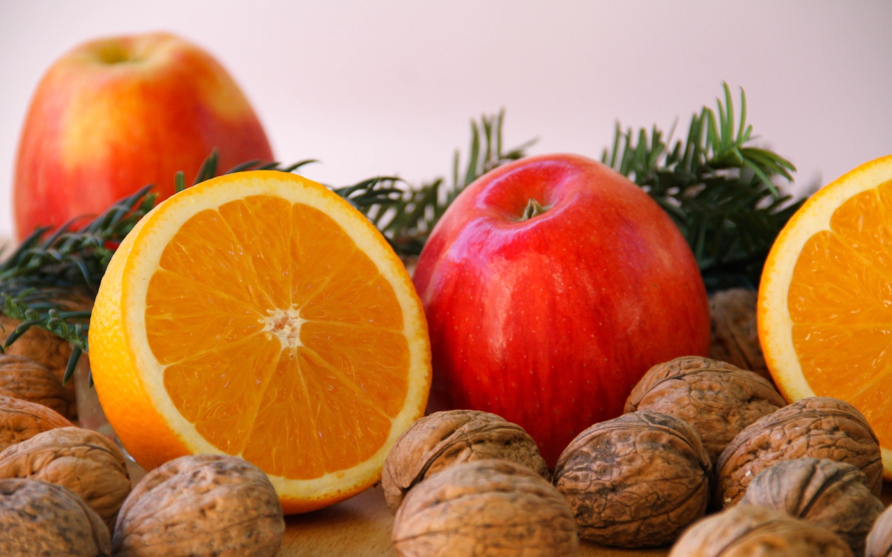 Грецкие орехи с апельсинами и яблоками на сером фоне 