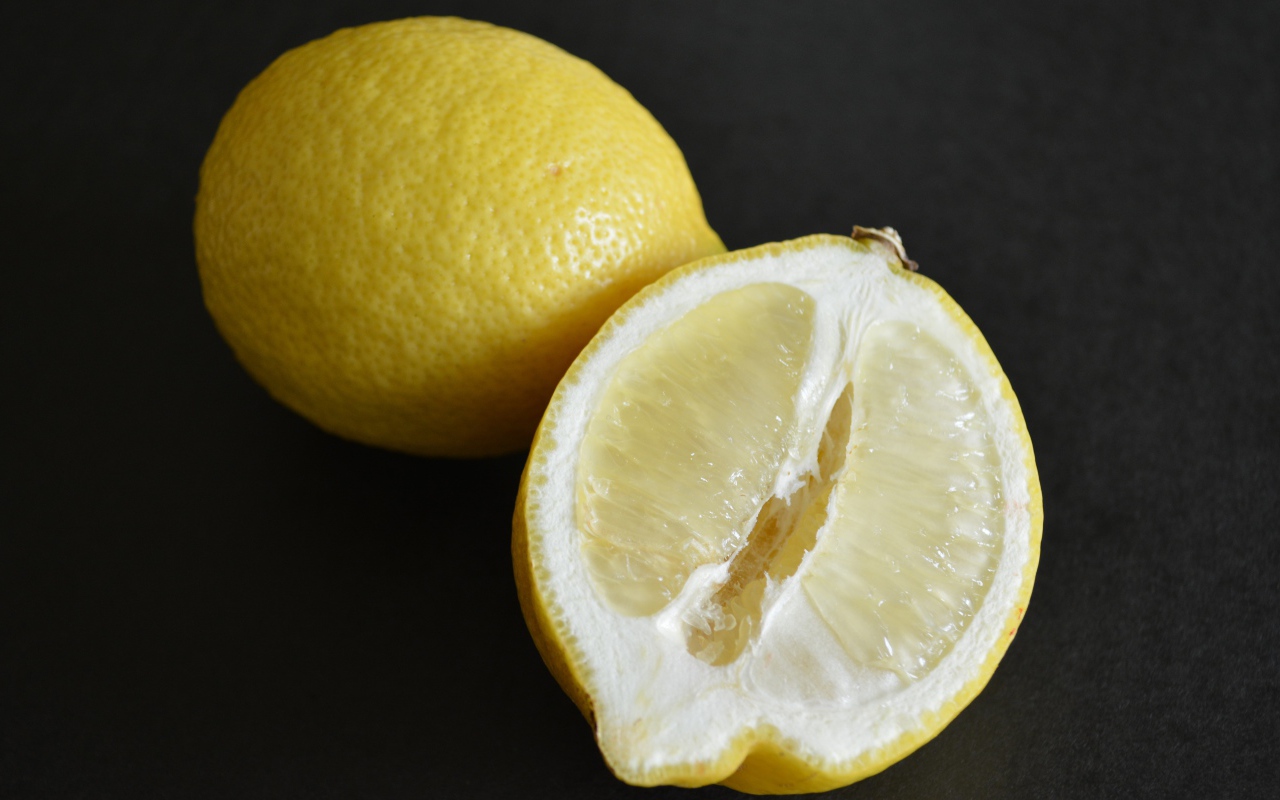 Целый лимон и половина на черной поверхности