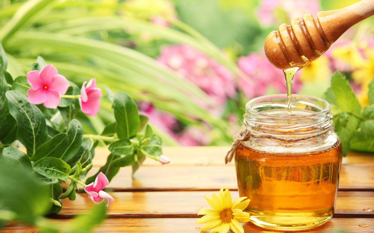 Банка ароматного меда на столе с цветами