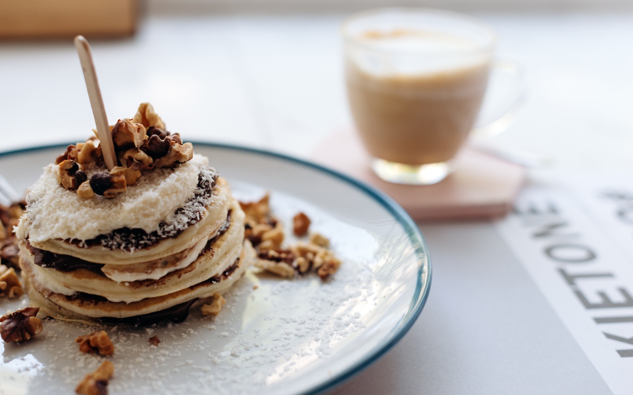Жареные оладьи со сметаной на тарелке с грецкими орехами 