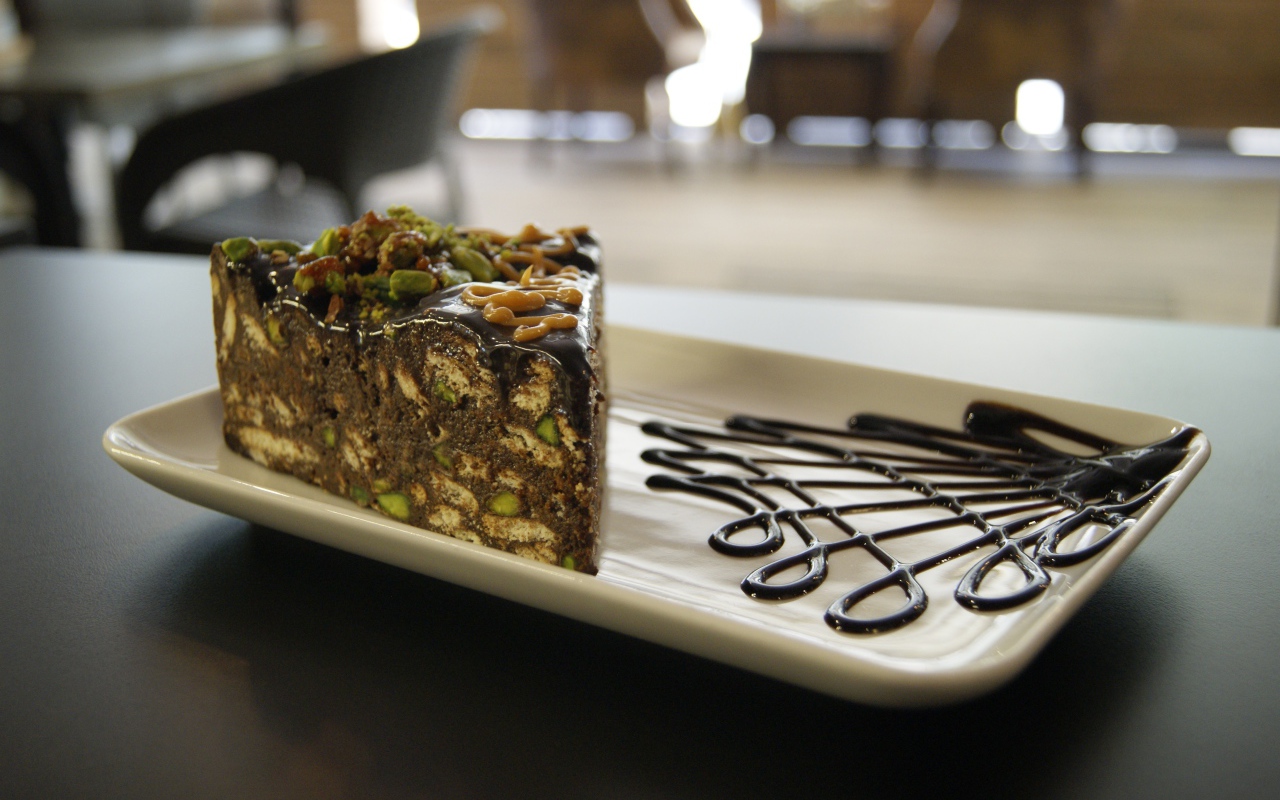 Кусок торта с фисташками на белой тарелке 