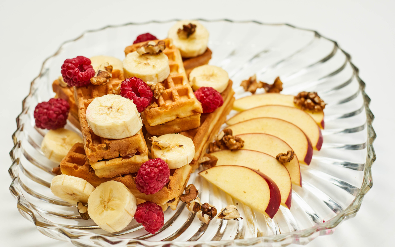 Сладкие вафли на тарелке с бананом, малиной и яблоком