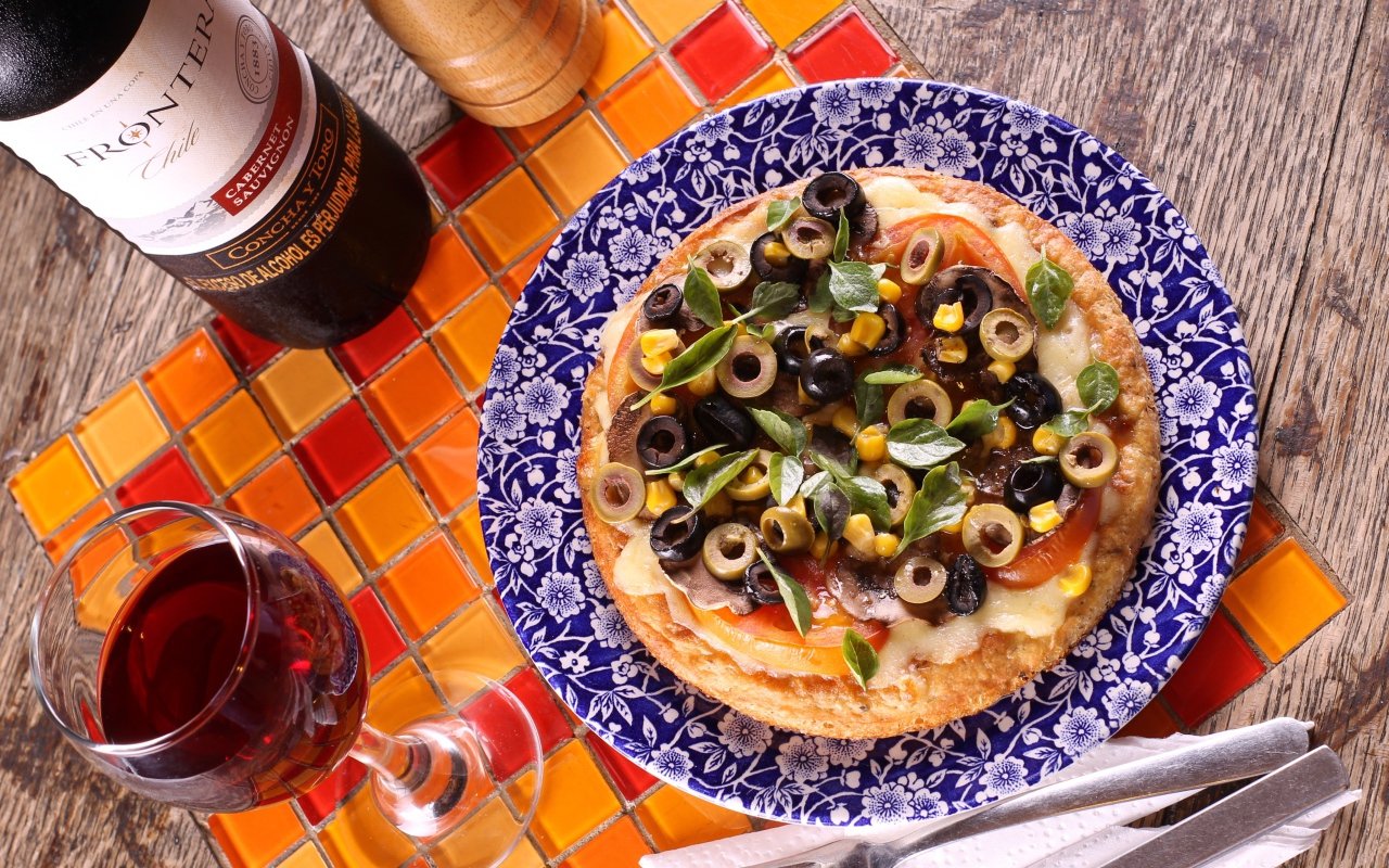 Итальянская пицца с оливками на столе с вином