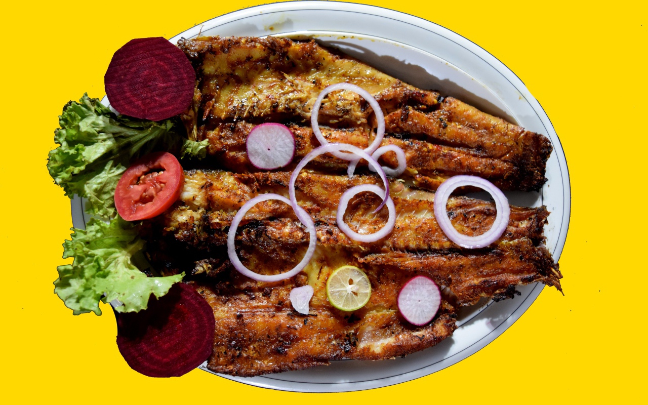 Жареная рыба с листьями салата, помидорами и свеклой на желтом фоне