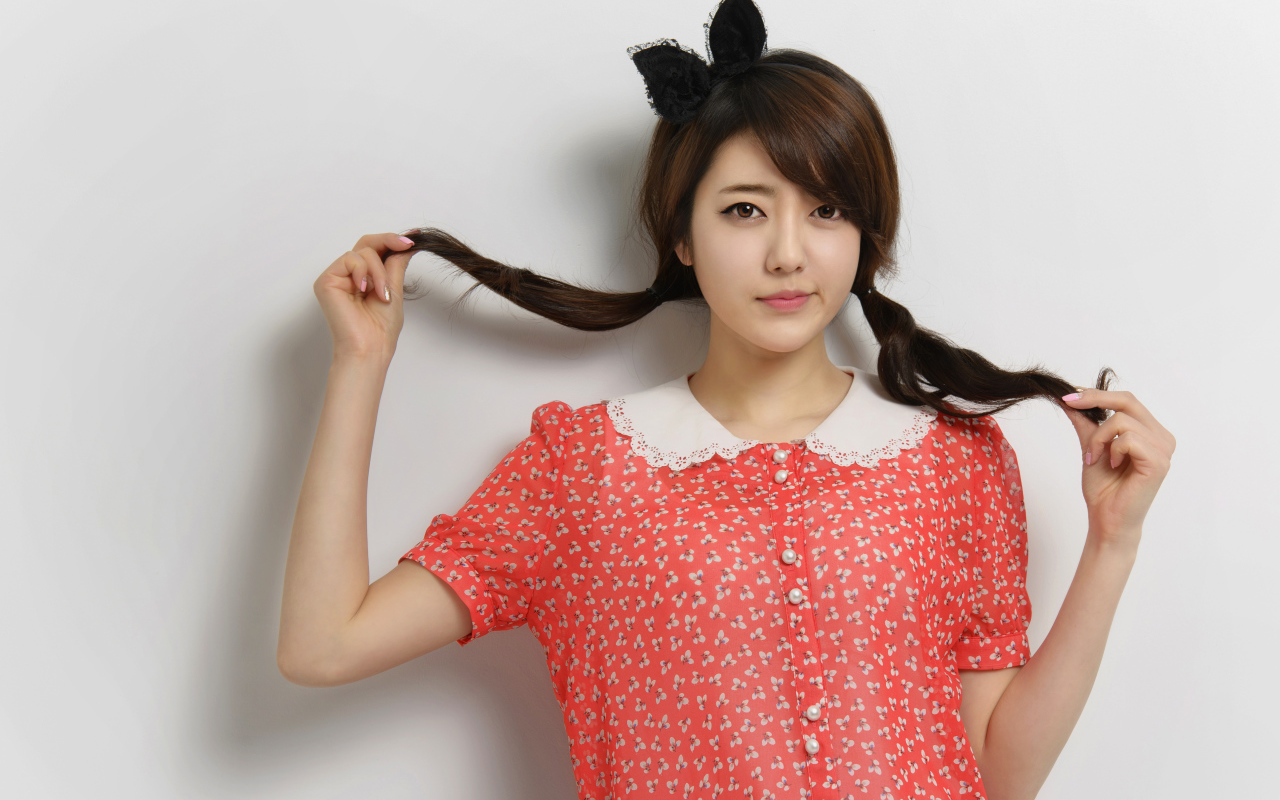 Девушка азиатка в платье стоит у стены 