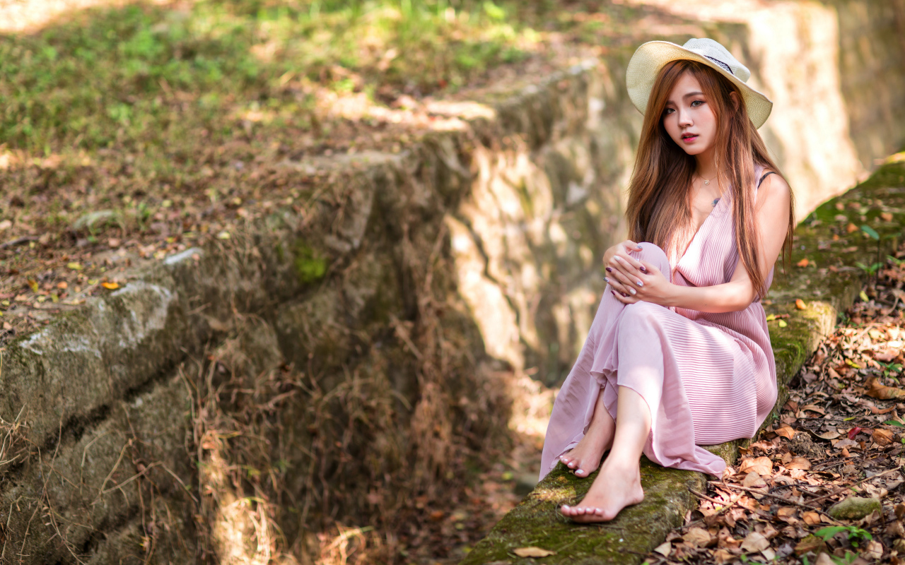 Девушка азиатка в розовом платье сидит на земле