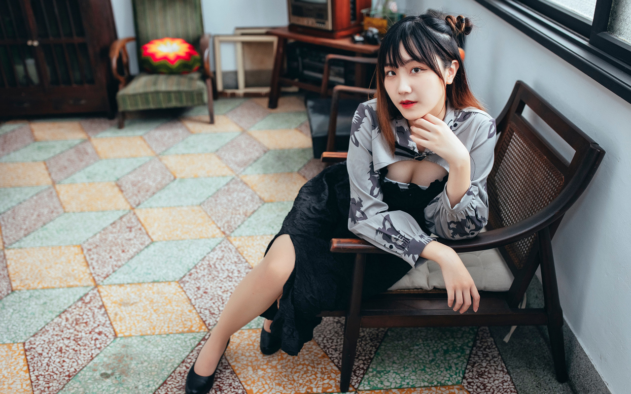 Девушка азиатка сидит на стуле в комнате 