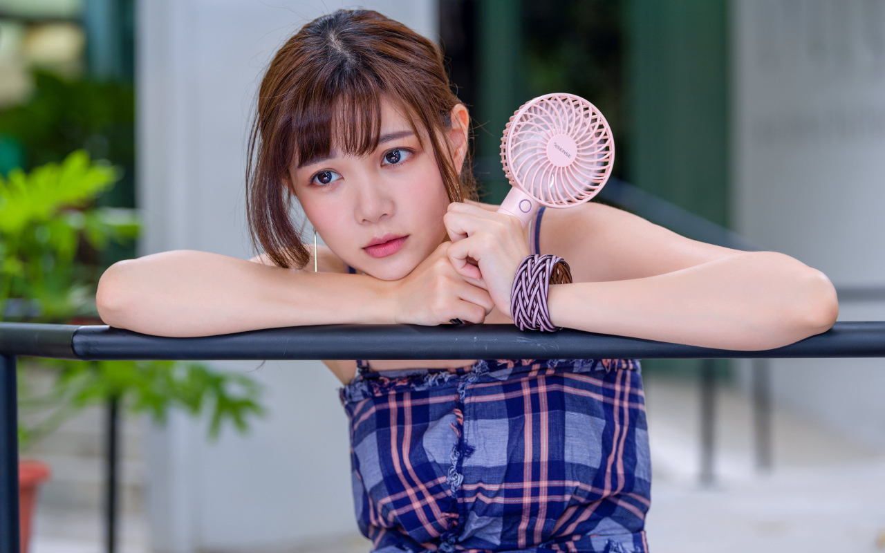 Девушка азиатка с вентилятором в руке 