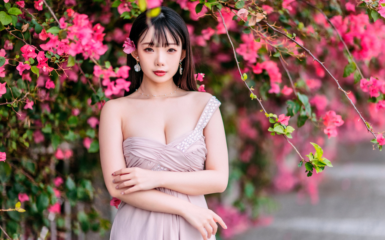 Красивая девушка азиатка у куста с  красными цветами 