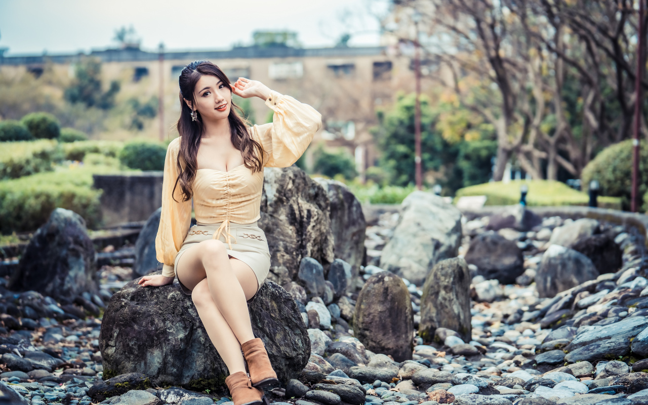 Красивая девушка азиатка сидит на камне