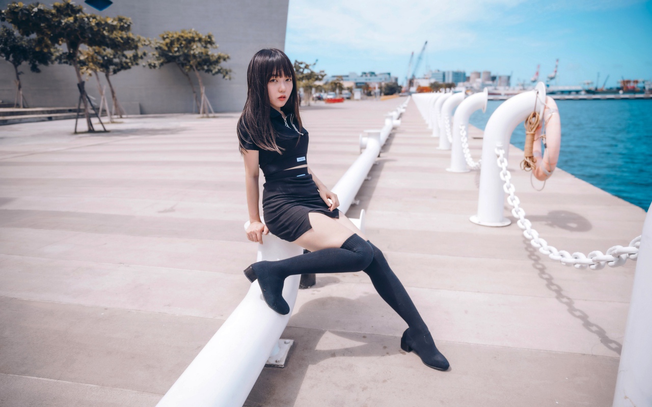 Красивая девушка азиатка в черных сапогах на причале