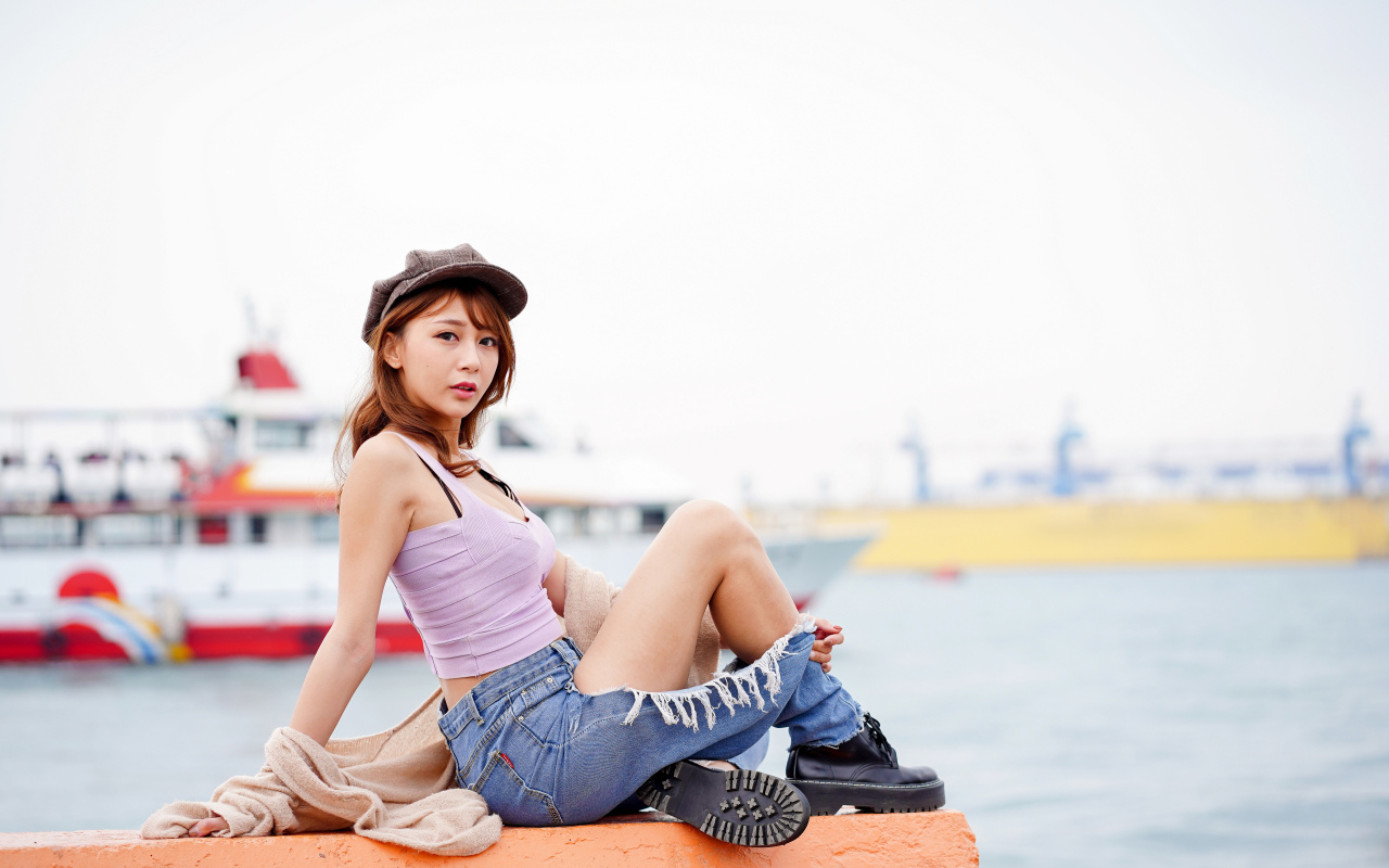Красивая девушка азиатка в джинсах у моря