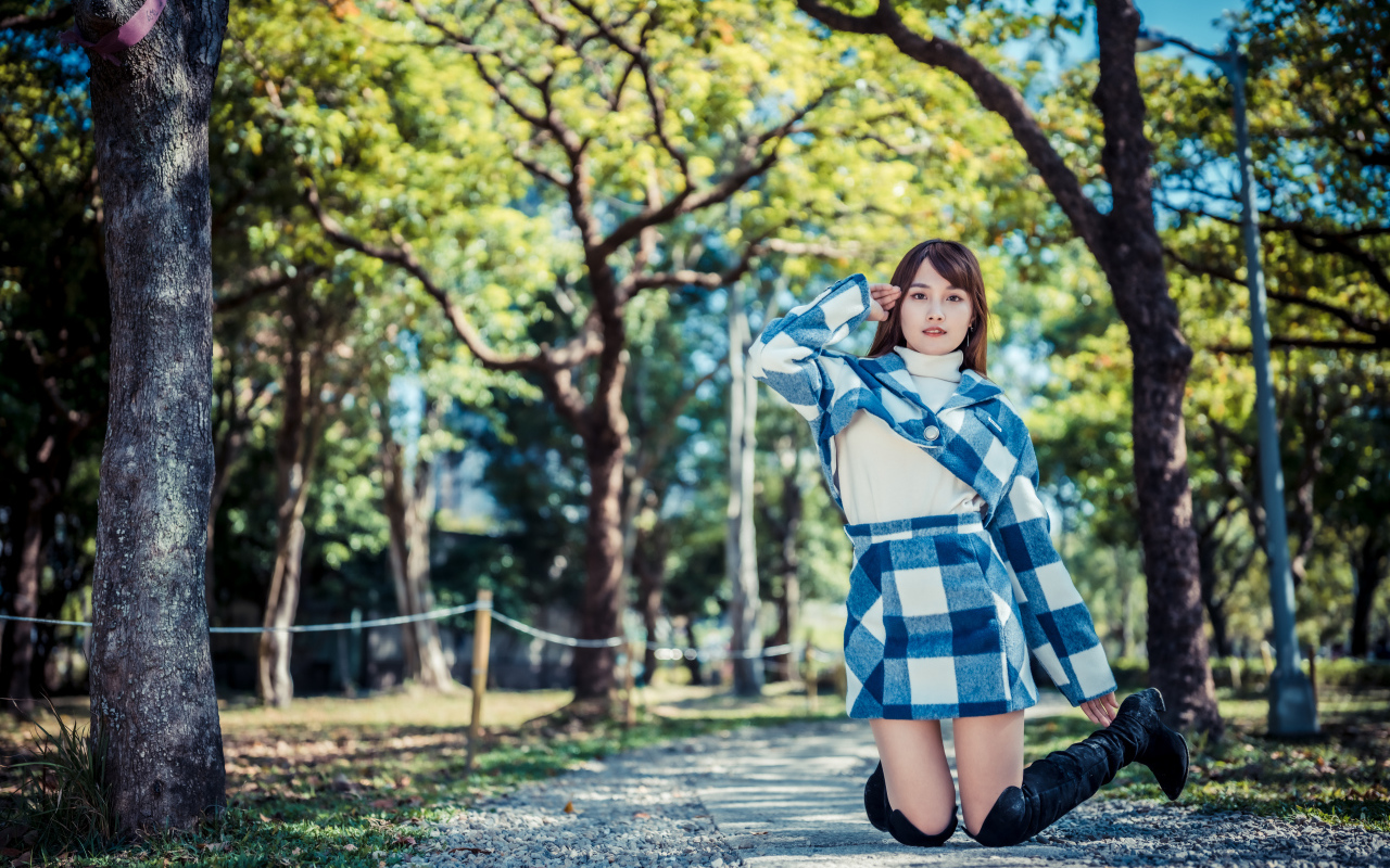 Красивая девушка азиатка стоит на коленях в парке