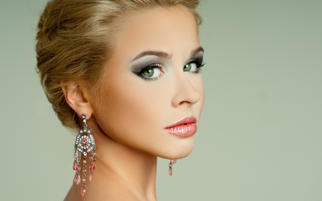 Красивая девушка блондинка с красивыми сережками на сером фоне