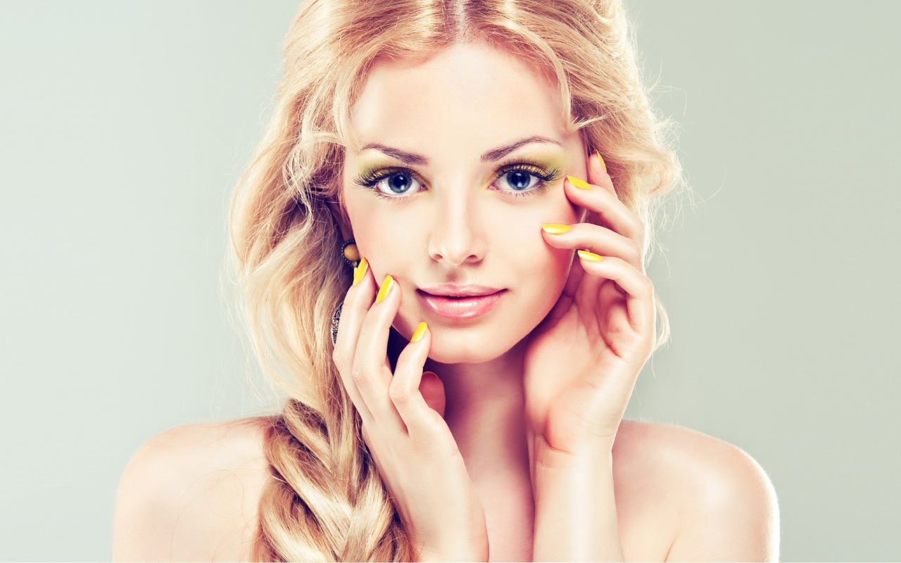 Красивая голубоглазая блондинка с желтым маникюром на руках 