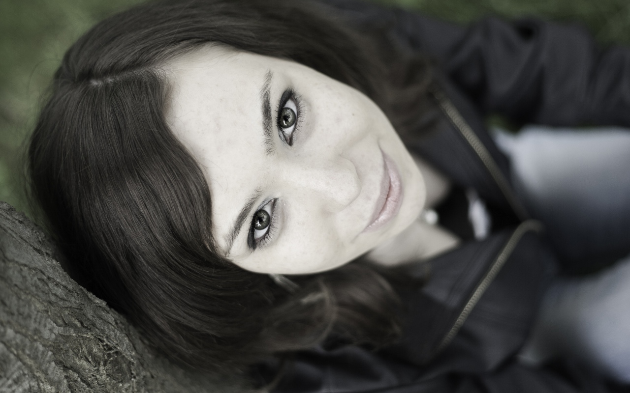 Красивая девушка смотрит вверх сидя под деревом  