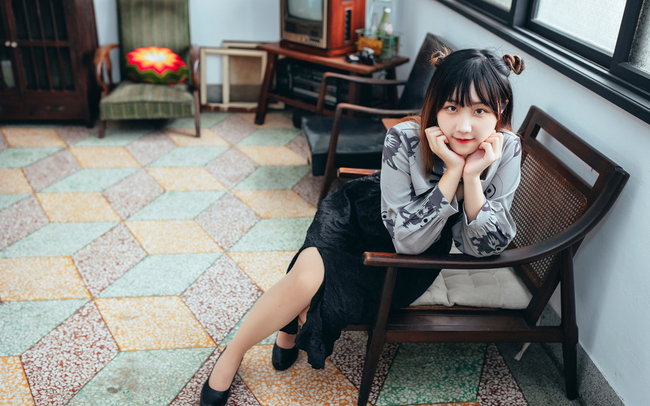 Красивая молодая азиатка сидит в кресле