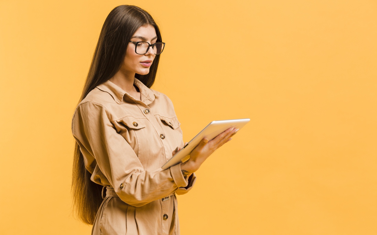 Девушка с планшетов руках на желтом фоне
