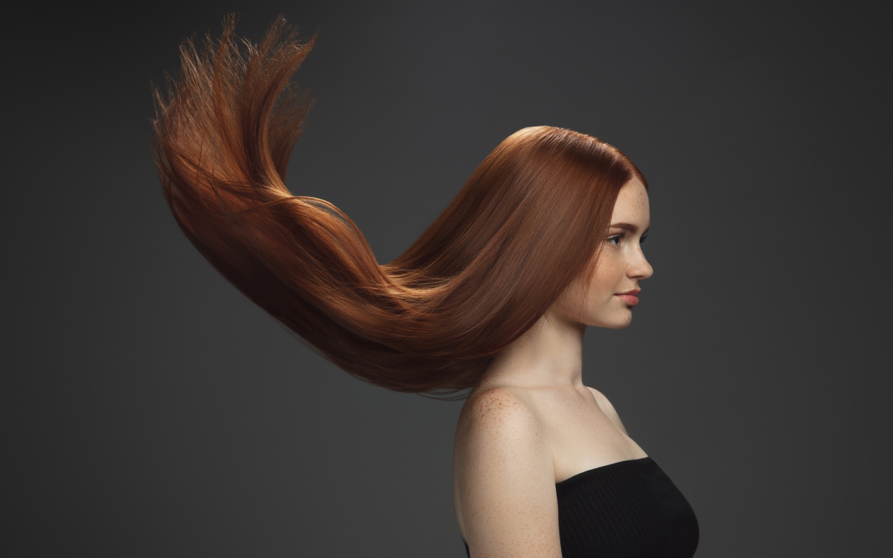 Волосы подняты вверх у красивой девушки на сером фоне