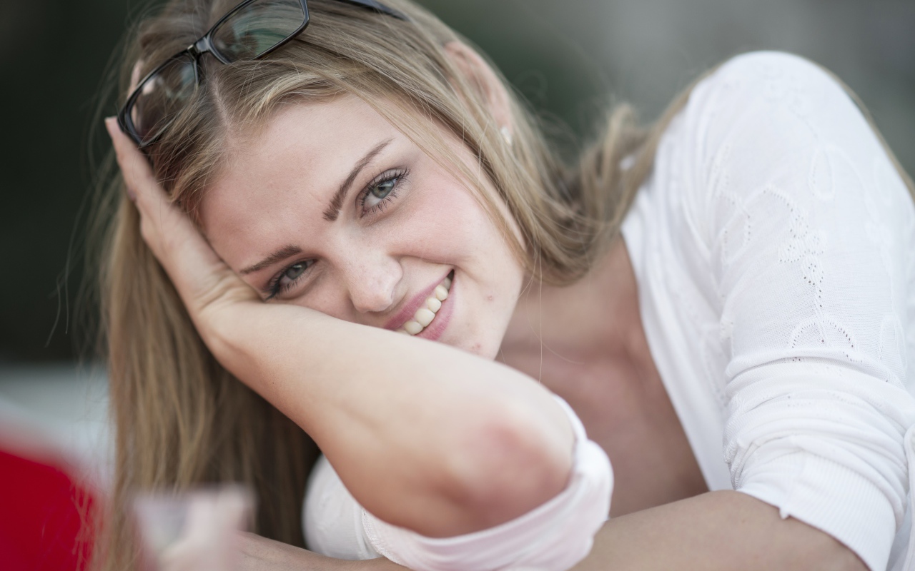 Улыбающаяся девушка блондинка с очками на голове