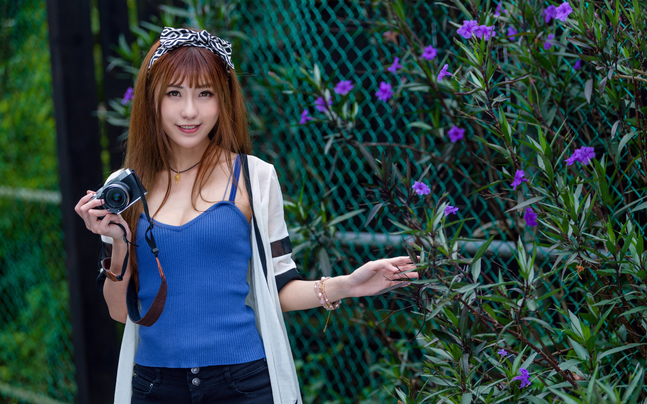 Улыбающаяся девушка фотограф стоит у сетки 