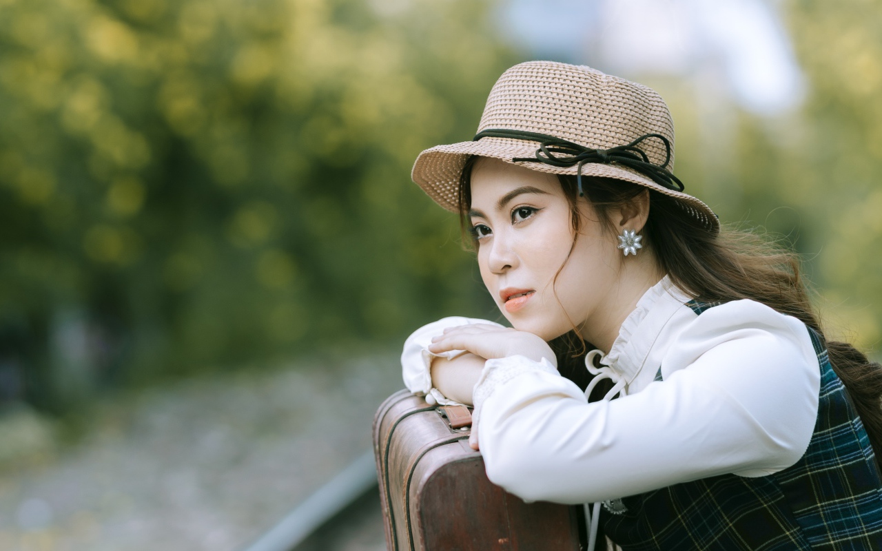 Молодая азиатка в шляпе с чемоданом