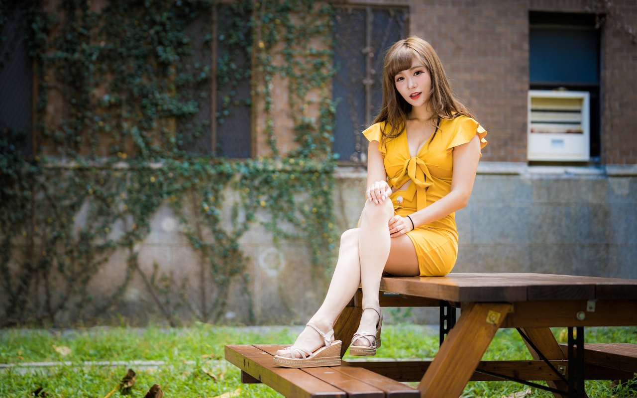 Молодая азиатка сидит в парке на столе 