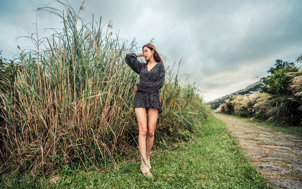 Молодая девушка азиатка стоит у зеленой травы