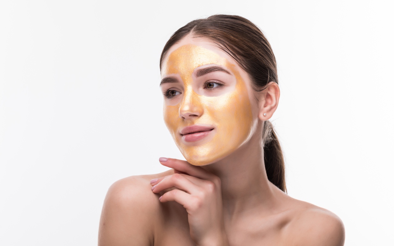 Молодая девушка без макияжа с золотой маской на лице