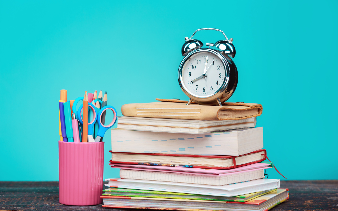 Будильник, книги и канцелярские предметы для школы