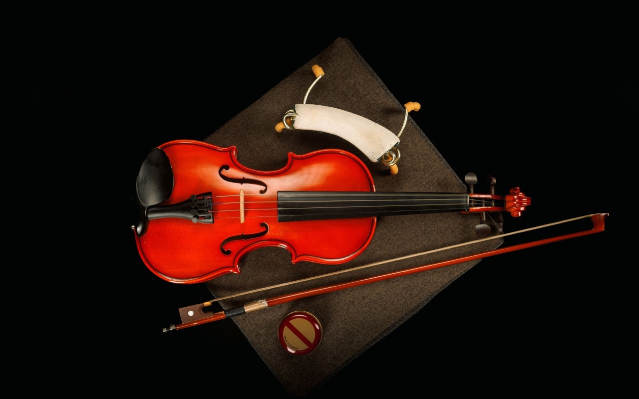 Red violin with bow on black background