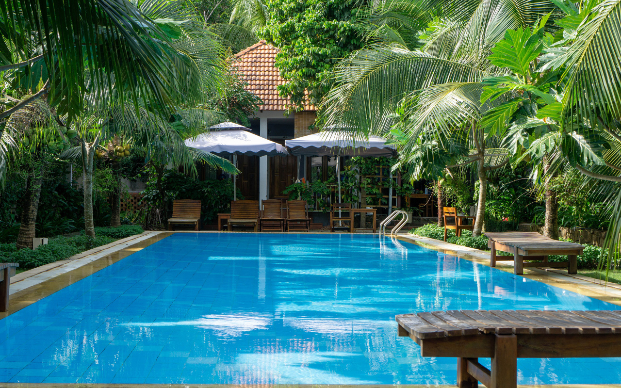 Бассейн с голубой водой у дома под пальмами