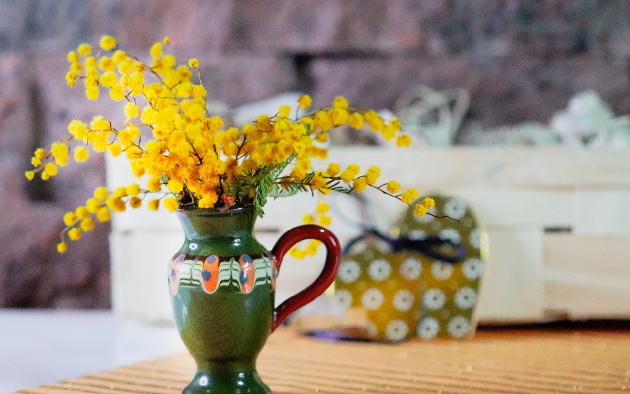 Желтые цветы мимозы в маленькой вазе на столе