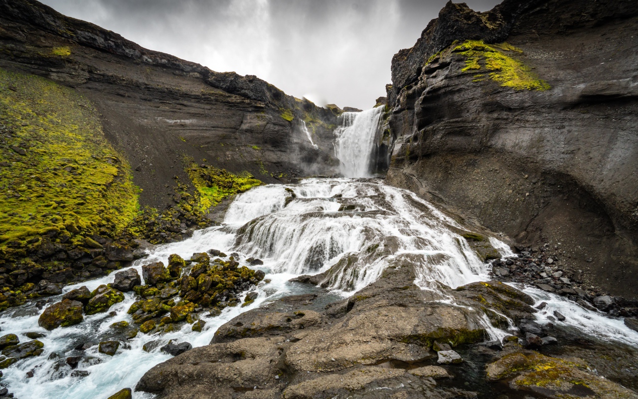 Быстрый горный водопад под серым небом