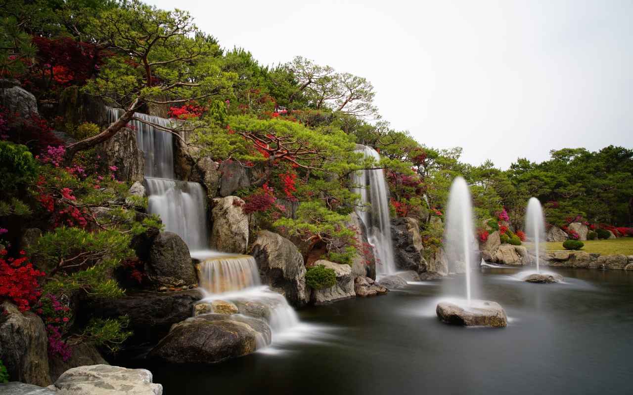 Водопады в красивом саду с зелеными деревьями
