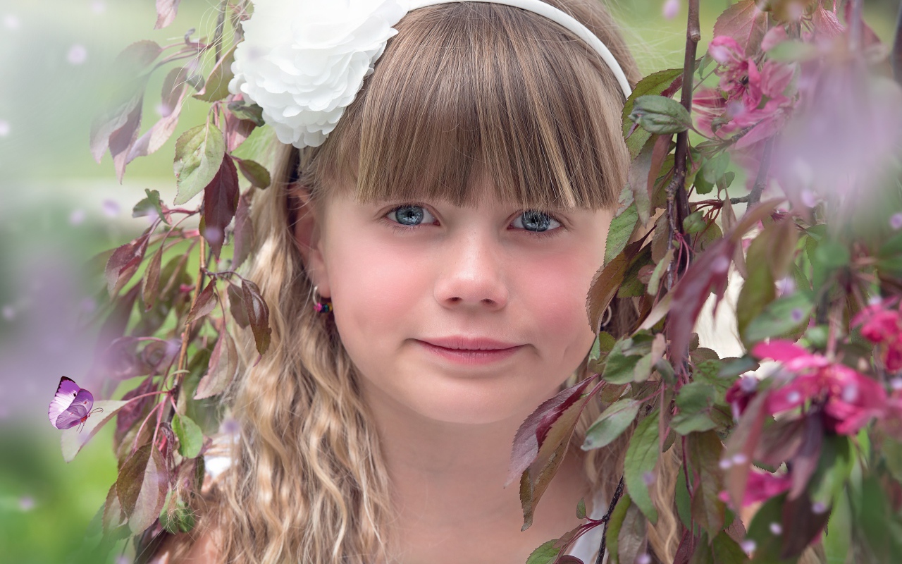 Красивая голубоглазая девочка с белым цветком на голове 