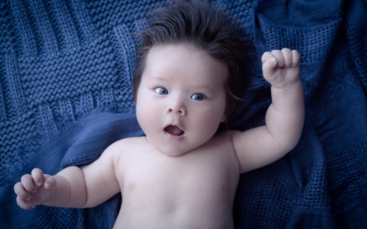 Мальчик с густыми волосами на синем покрывале 