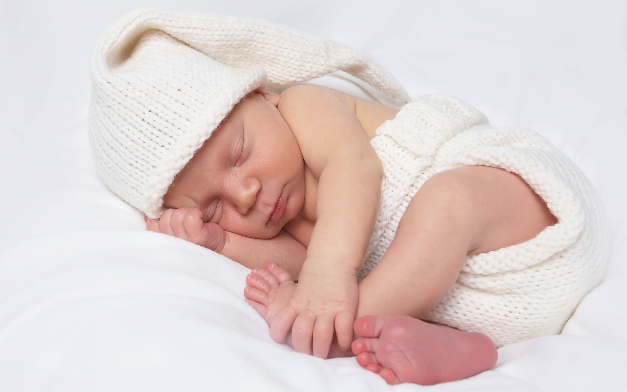 Нежный новорожденный ребенок в белом костюме