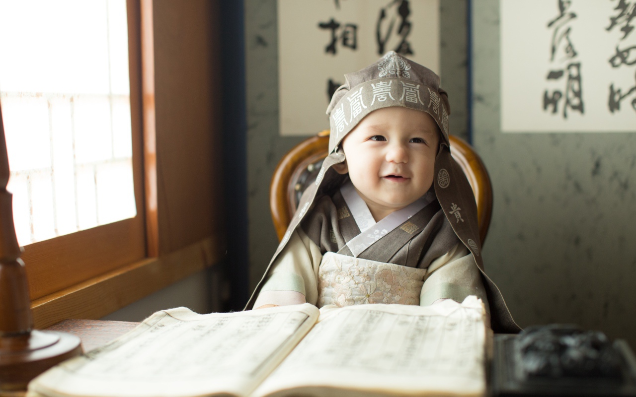 Маленький азиатский мальчик за столом с книгой