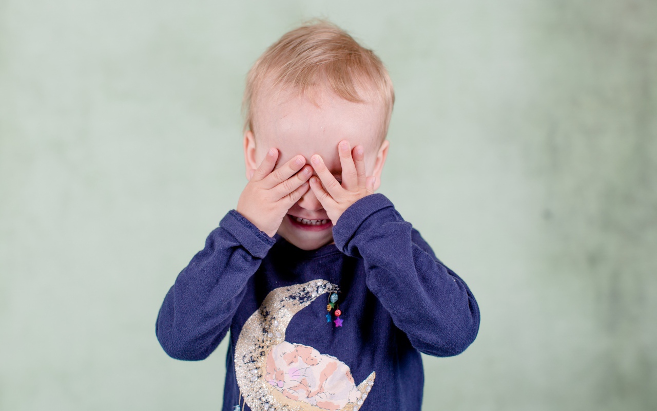 Маленький мальчик закрыл руками лицо 