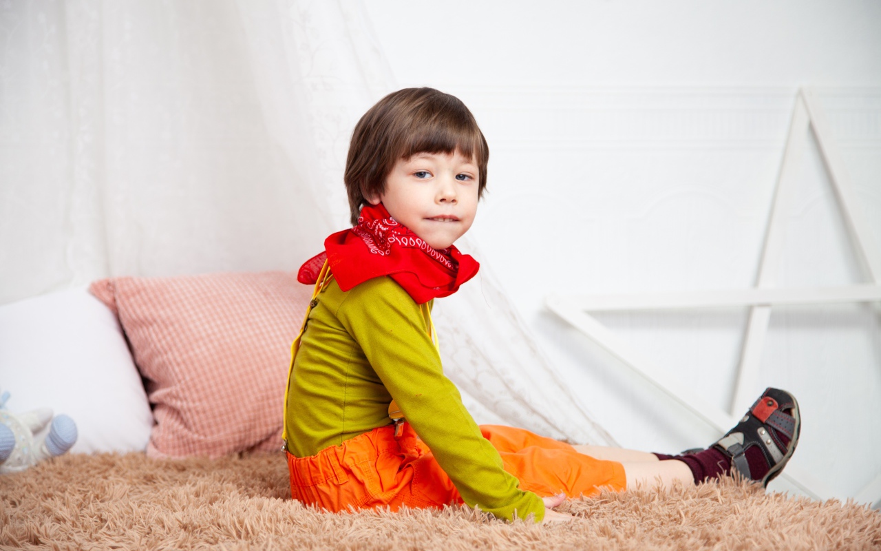 Маленький мальчик сидит на кровати