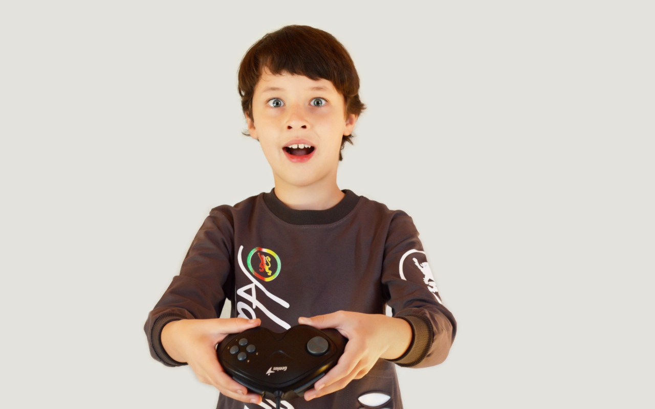 Маленький мальчик с приставкой на сером фоне 